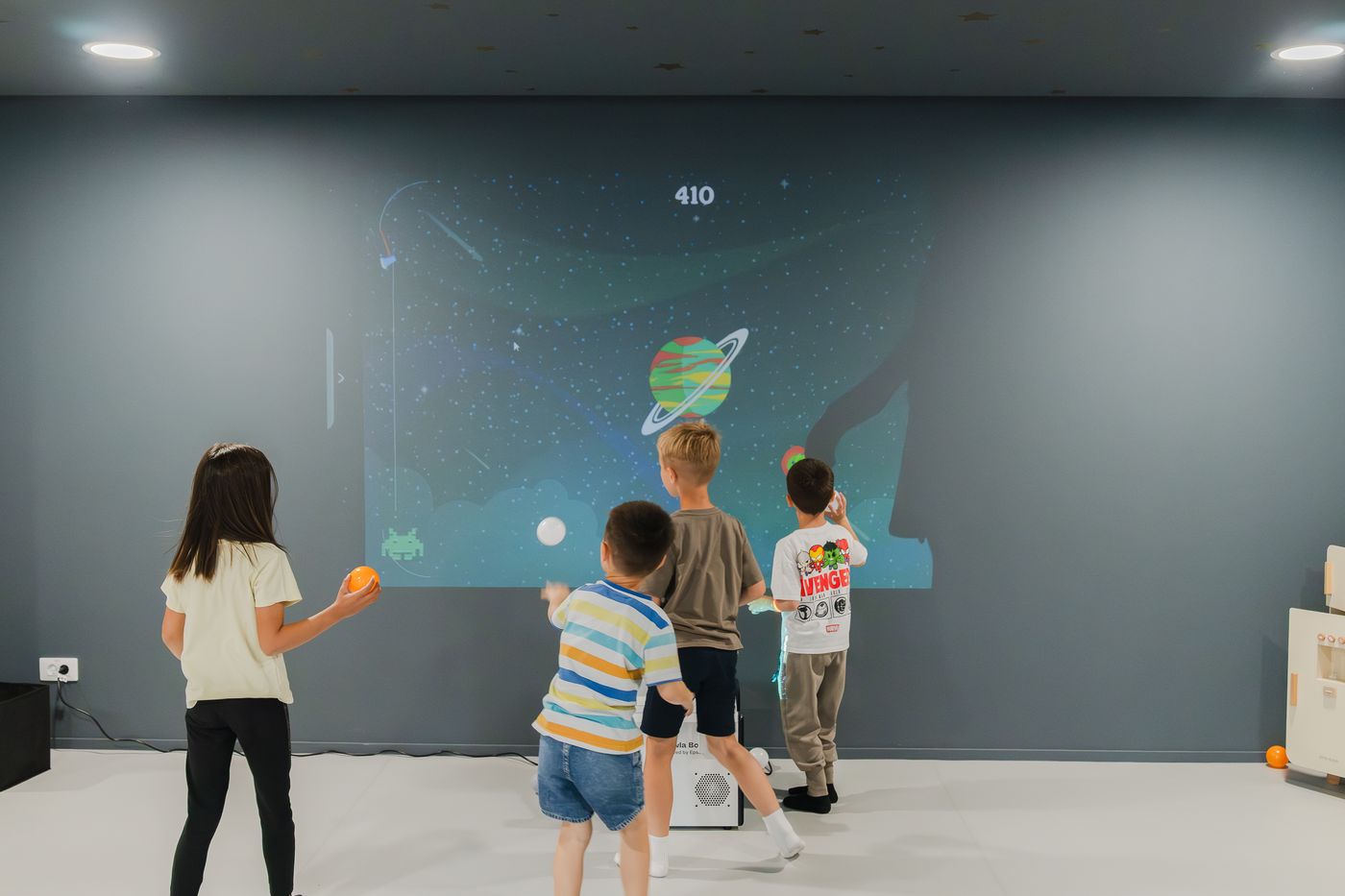Copii explorând un joc interactiv pe perete